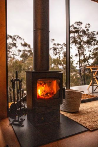 a fireplace in a room with a view of trees at Off-Grid Cabin Surrounded by Nature - Emillie in Oberon