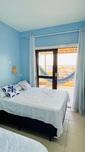 a bedroom with a large bed and a large window at Todo Azul do Mar in Taíba
