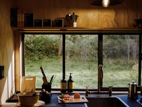 ein Küchenfenster mit Blick auf ein Feld in der Unterkunft Off-Grid Cabin Deep in Nature - Pet Friendly - Barney in Dingadee