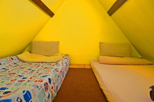 two beds in a room with yellow walls at Mundo Abu San Juan La laguna in San Juan La Laguna