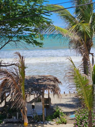 a beach with chairs and palm trees and the ocean at Los Pinos de Zorritos Condominio in Zorritos