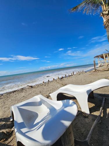a white chair sitting on a beach next to the ocean at Los Pinos de Zorritos Condominio in Zorritos