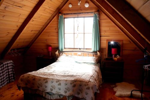 a bedroom with a bed in a attic with a window at Wombat Cabin in Moina