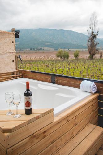 a bath tub with a bottle of wine and two glasses at Apalta Lofts, disfruta frente a viñedos in Santa Cruz