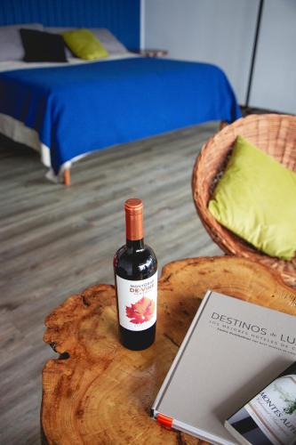 a bottle of wine sitting on a table next to a bed at Apalta Lofts, disfruta frente a viñedos in Santa Cruz