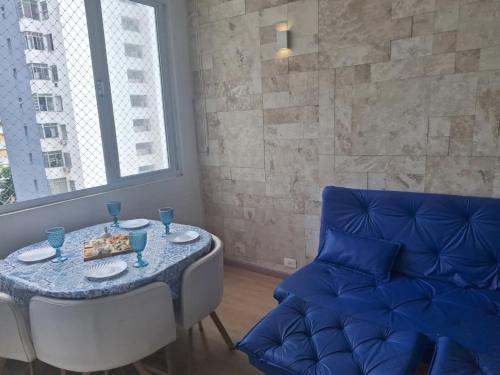 a dining room with a table and a blue couch at Beach House 2 in Guarujá