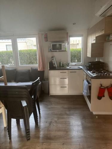une petite cuisine avec une table et une cuisinière dans l'établissement Mobil home climatisé 8 couchages 3 CHAMBRES 222 SIBLU LES CHARMETTES, aux Mathes