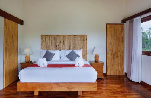 a bedroom with a large bed with two white towels at Desa Di Bali Villas in Kerobokan