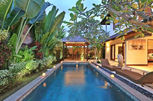 a swimming pool in a garden with a house at Desa Di Bali Villas in Kerobokan