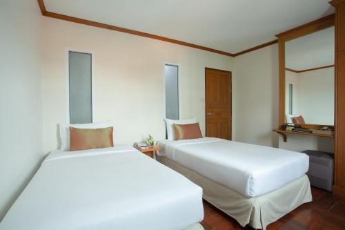 two beds in a hotel room with white sheets at Khum Phucome Hotel -SHA Extra Plus in Chiang Mai