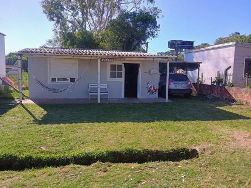 a small white house with a car parked in the yard at PRAZER, Casa de Vacaciones en Barra del Chuy, Sol, Mar, Comodidad y compras a 400 mts del mar, se reserva con seña! in Barra del Chuy