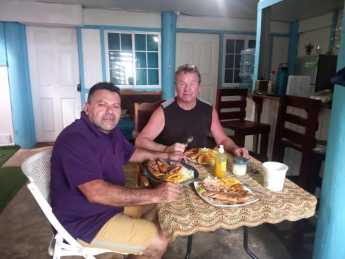 two men sitting at a table with a plate of food at Hotel Victoria s Beach House in Roatan