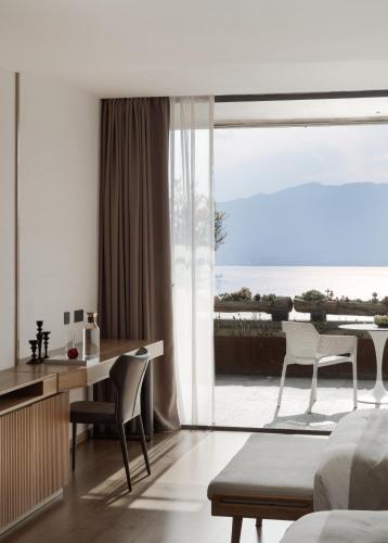 a bedroom with a desk and a view of the ocean at Skyline Cloud Cliff Sea View Hotel in Dali