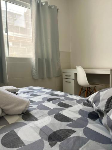 a bedroom with a bed and a desk and a window at Casa com salão de festas 7km da praia in Camboriú