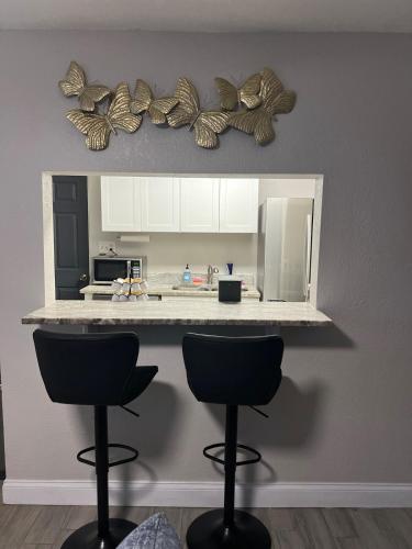 a kitchen with two bar stools and a mirror with butterflies at City and Stadium Sanctuary Vibes in Orlando
