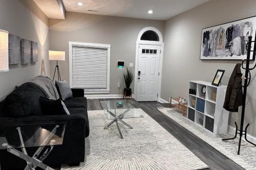 a living room with a black couch and a glass table at Modern Comfort in Historic East Baltimore Stylish 3BR Row Home in Baltimore