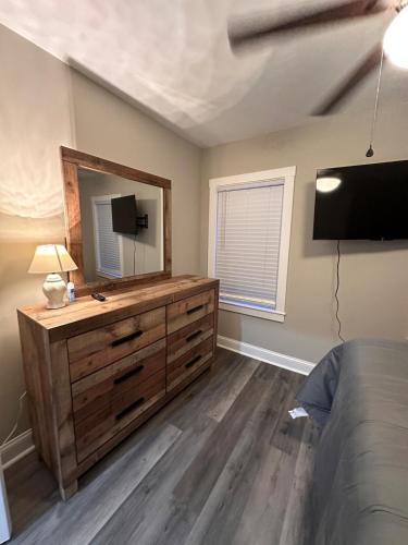 a bedroom with a dresser with a mirror and a television at Modern Comfort in Historic East Baltimore Stylish 3BR Row Home in Baltimore