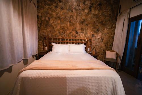 a bed in a room with a stone wall at Saona Bangalôs Taíba in Taíba