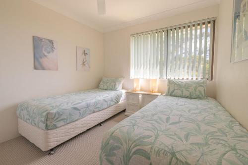 a bedroom with two beds and a window at Intrepid 12 right on the beachfront in Shoal Bay