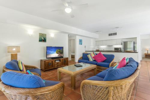 a living room with two couches and a tv at Balboa Apartments in Port Douglas