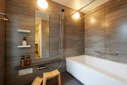 a bathroom with a white tub and a mirror at Minn Kitahiroshima Station East in Nakanosawa