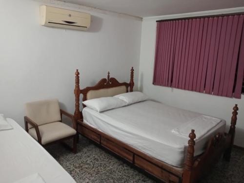 a bedroom with a bed and a chair and a window at Tranquila y cerca de la magia in Cartagena de Indias