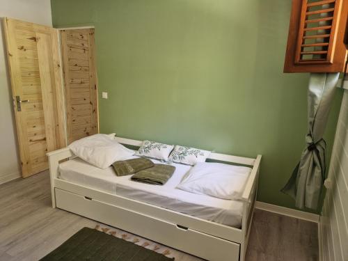a small bed in a room with green walls at Bungalow Colibris de MEDi in Goyave