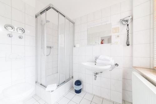 een witte badkamer met een douche en een wastafel bij ArtHotel City in Neurenberg