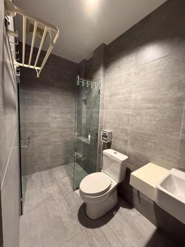 a bathroom with a toilet and a shower and a sink at Riverine Diamond Condominium at City Centre in Kuching