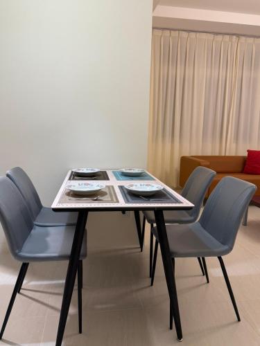 a table with two blue chairs and a couch at Riverine Diamond Condominium at City Centre in Kuching