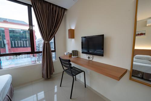 a room with a desk with a tv and a chair at Green Hotel in Puchong