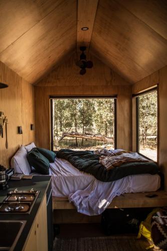 a bedroom with a bed in a cabin with a window at Off-Grid Cabin in the Hunter Valley - Hazel in Pokolbin