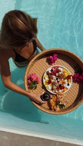 a woman holding a plate of food in a pool at Casa Roni by Xeno - 5 Bedroom Luxury Villa with Ocean View in Playa Estacahuite