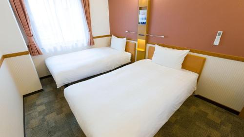 two beds in a small room with white sheets at Toyoko Inn Yamagata-eki Nishi-guchi in Yamagata