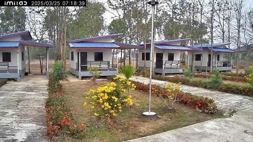 a row of cottages with blue roofs and flowers at Banromsak resort - บ้านร่มสักรีสอร์ต in Ban Dok Kham Tai (1)