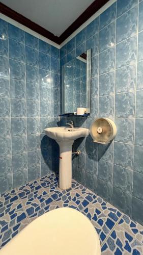 a blue tiled bathroom with a sink and a mirror at Green Hotel in Pattaya South