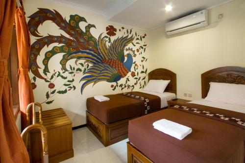 a bedroom with two beds and a peacock painting on the wall at De Hostel Yogyakarta in Yogyakarta