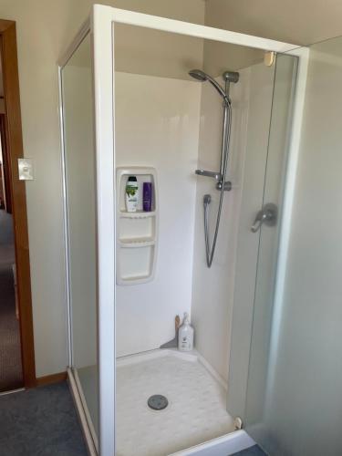 a shower with a glass door in a bathroom at 49 on Jans Beach Break in Oakura