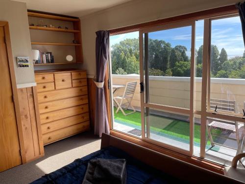 a room with a large window with a view of a yard at 49 on Jans Beach Break in Oakura