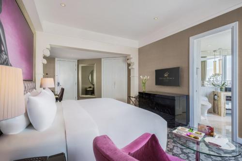 a bedroom with a large white bed and a living room at Hotel Ciputra World Surabaya managed by Swiss-Belhotel International in Surabaya