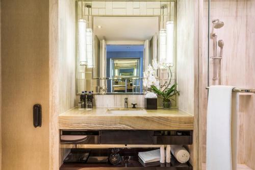 a bathroom with a sink and a large mirror at Hotel Ciputra World Surabaya managed by Swiss-Belhotel International in Surabaya