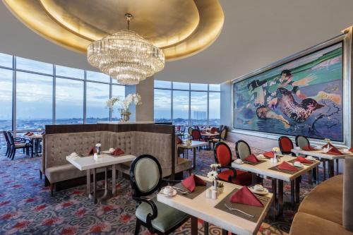 a restaurant with tables and chairs and a chandelier at Hotel Ciputra World Surabaya managed by Swiss-Belhotel International in Surabaya