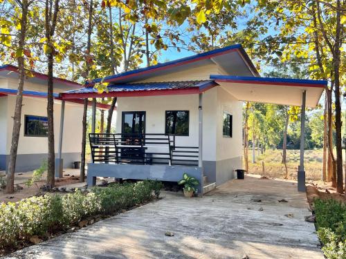 a small white house with a porch at Banromsak resort - บ้านร่มสักรีสอร์ต in Ban Dok Kham Tai (1)