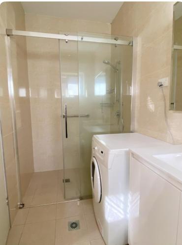 a bathroom with a shower and a washing machine at Entire Studio Guesthouse in East Lindfield in Roseville