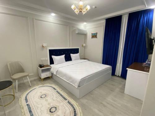 a bedroom with a large white bed and blue curtains at Beksaroy in Samarkand