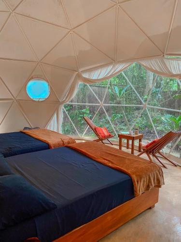 a bedroom with two chairs and a bed in a tent at Ku kuk Glamping in Chemuyil