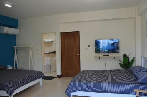 a bedroom with two beds and a tv on the wall at Kinmen Fujian Homestay in Tung-chou