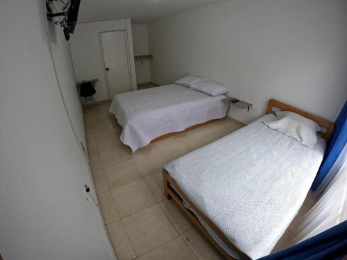 two beds in a small room with a window at Bacata Housing in Bogotá