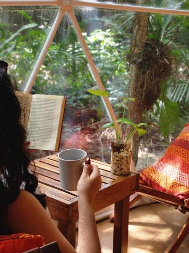 a woman sitting at a table reading a book at Ku kuk Glamping in Chemuyil