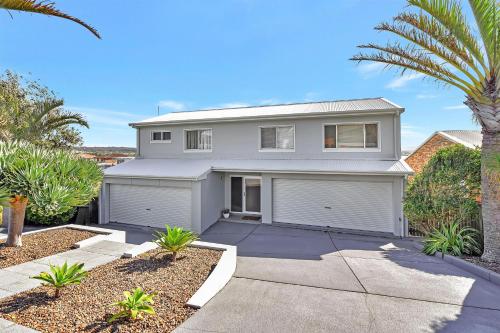 a white house with a garage and palm trees at The Sea Serenade in Blacksmiths
